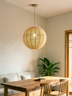 A wood bench-seated table and a leafy plant sit near a window, lit by this hemp rope Clérachic pendant.