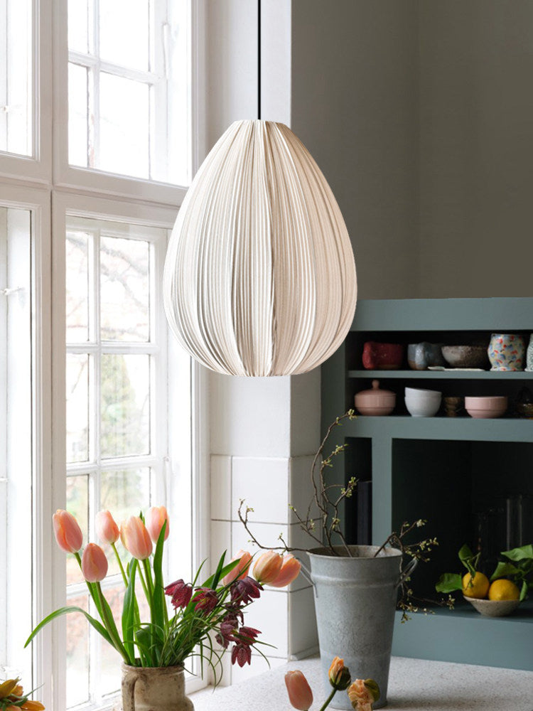 This Clérachic pendant's egg-shaped shade hangs beside a window with tulips in a vase and a teal cabinet.