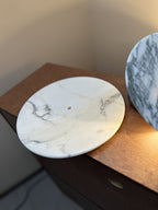 A second overhead close-up shows a paler, grey-veined Clérachic marble disc lying flat, its centre hole visible in daylight.