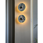 Two Clérachic marble wall lights glow warm amber on a wall pillar, with a light switch plate visible beside the lower fixture.