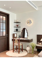 The widest version of this entryway scene shows the glowing Clérachic wall light beneath a vented ceiling, with the cat and mirror below.
