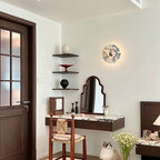 A taller crop of the same entryway shows the glowing Clérachic wall light, the rattan stool, mirror, cat and dressing table in full.