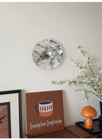 A tight crop shows the Clérachic wall light above a console, a lettered canvas print, an orange mushroom lamp and white blossoms.
