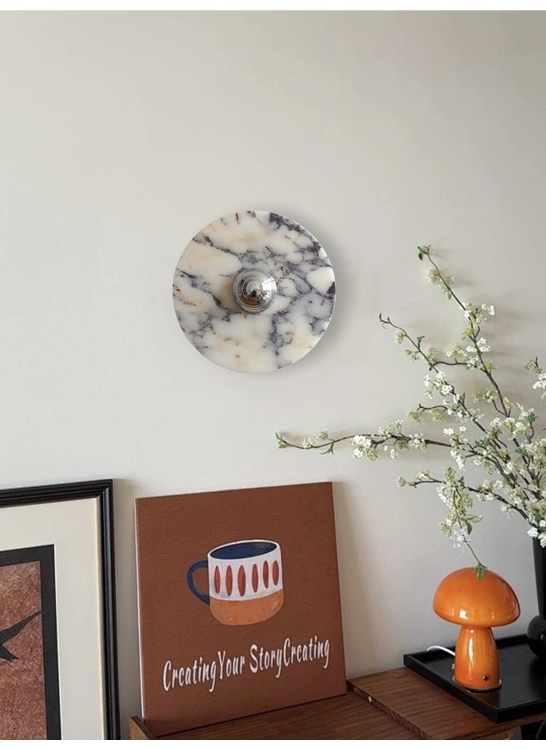 A tight crop shows the Clérachic wall light above a console, a lettered canvas print, an orange mushroom lamp and white blossoms.