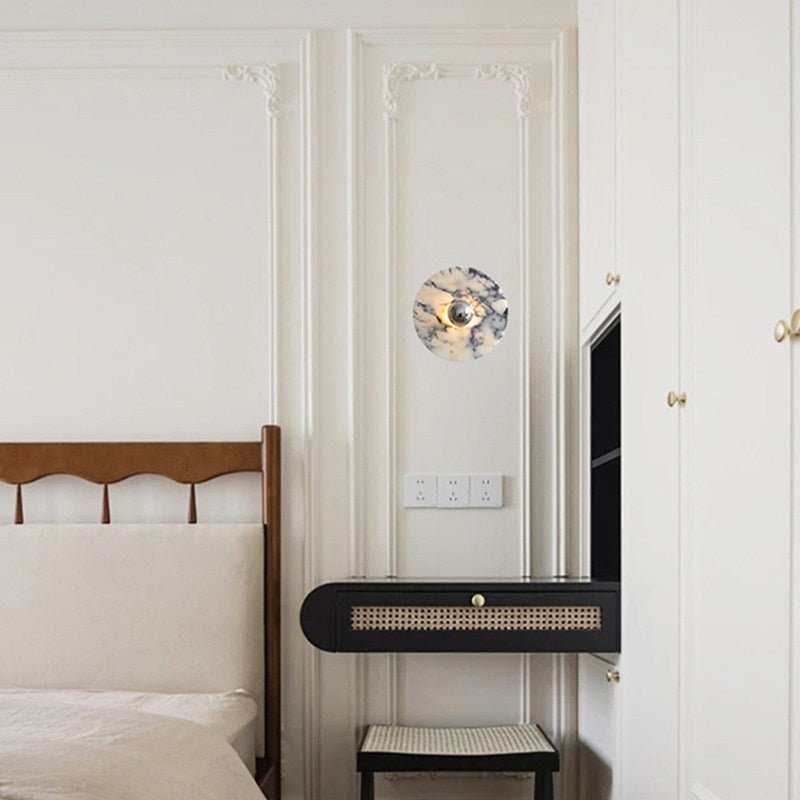 A wider view of the panelled corridor shows the same Clérachic wall light glowing above the cane bench, near a dark screen and door.