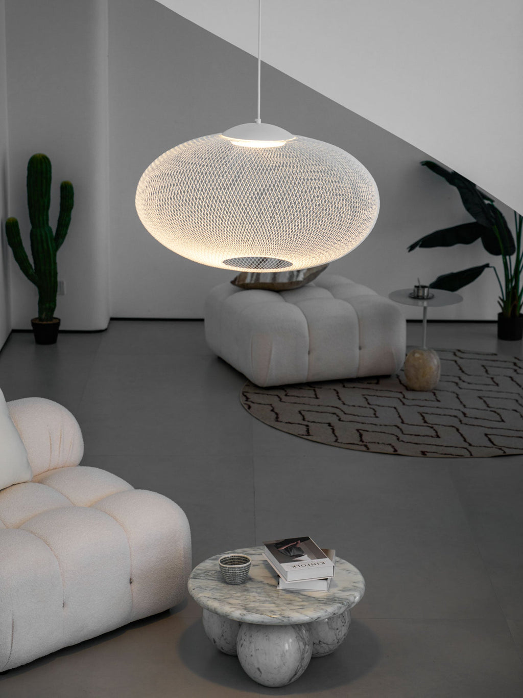 White mesh pendant light glowing over a dining setting