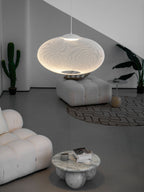 White mesh pendant light glowing over a dining setting