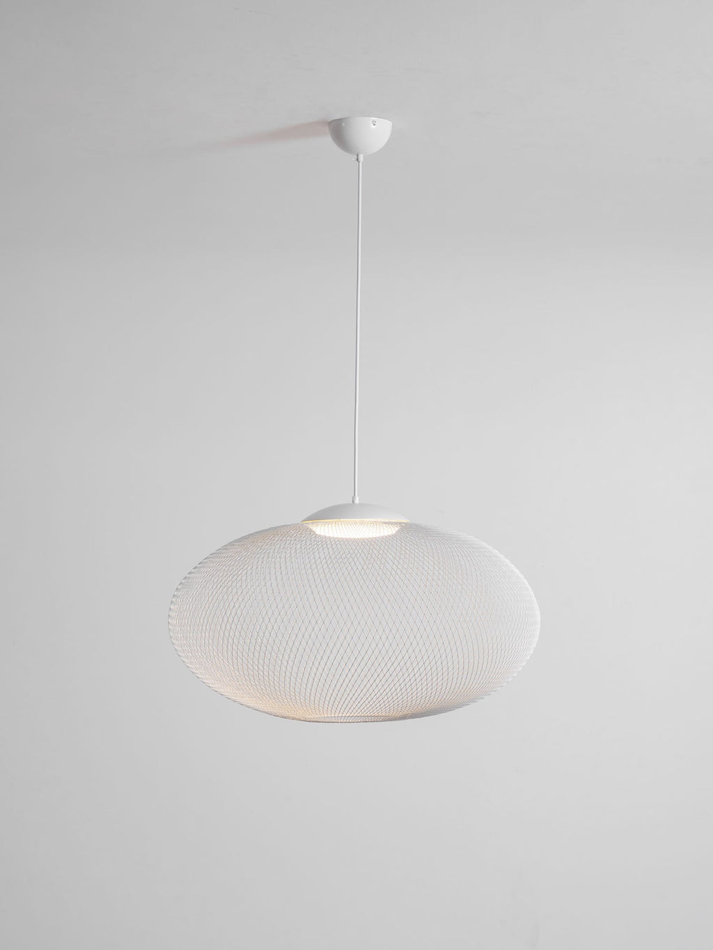 Mesh pendant light glowing warm above a seating area