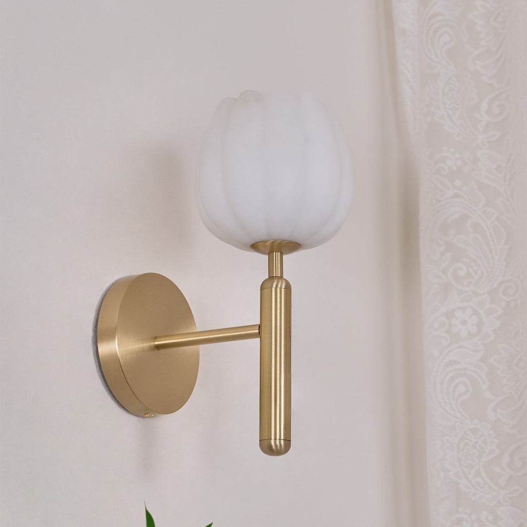 Brass Eurzorion wall light on a cream wall beside a lace curtain, angled to show the wall arm
