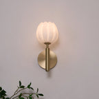 Eurzorion wall light glowing on a mauve-grey wall, viewed head-on with a leafy branch below