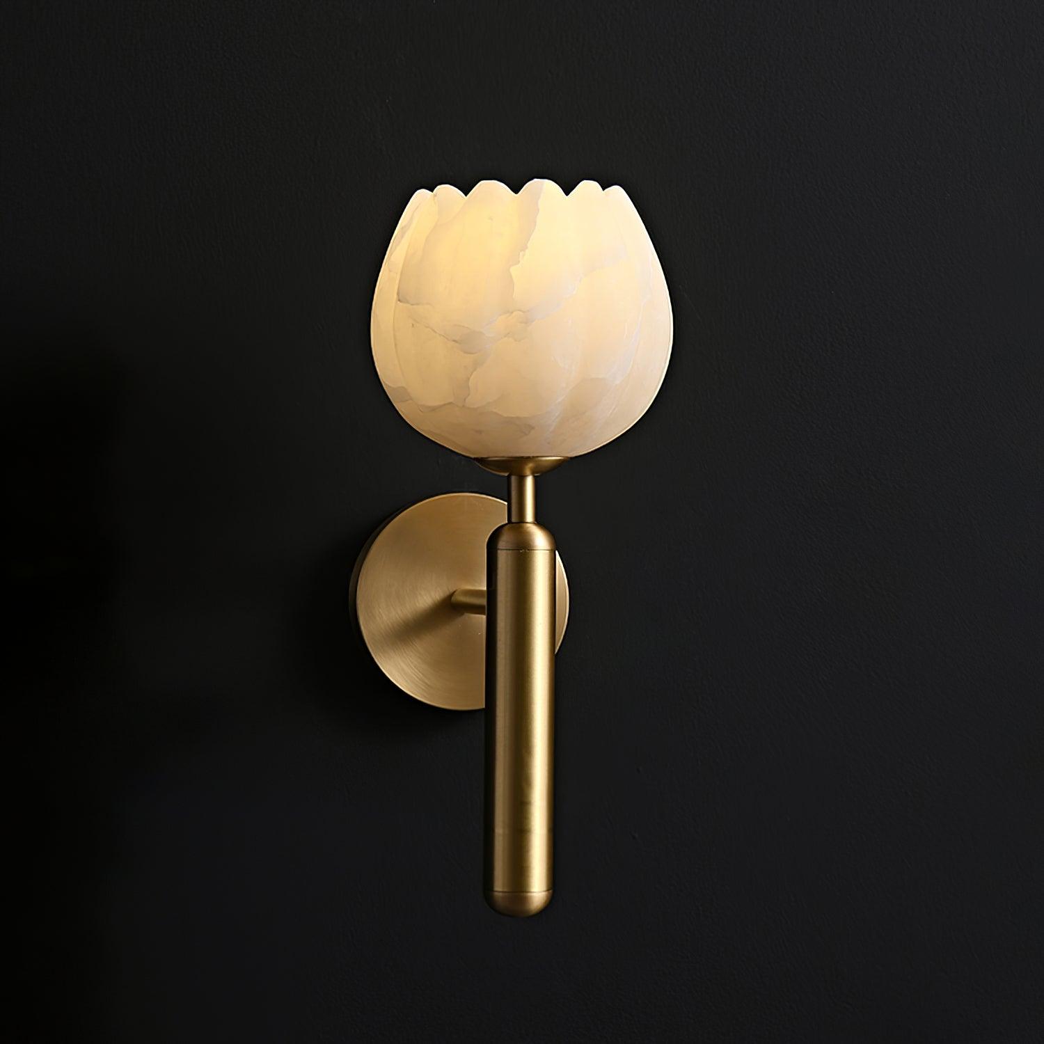 Warm-lit Eurzorion alabaster wall light in brass on a black wall, the shade glowing from within