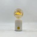 The word Home glows in the filament of this Clérachic novelty lamp's cognac-tinted bulb, set on a white marble base.