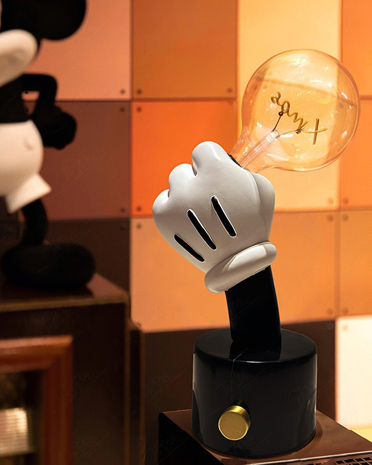 Clérachic novelty table lamp glowing against a red tiled wall, its white glove hand and black base lit warmly indoors.