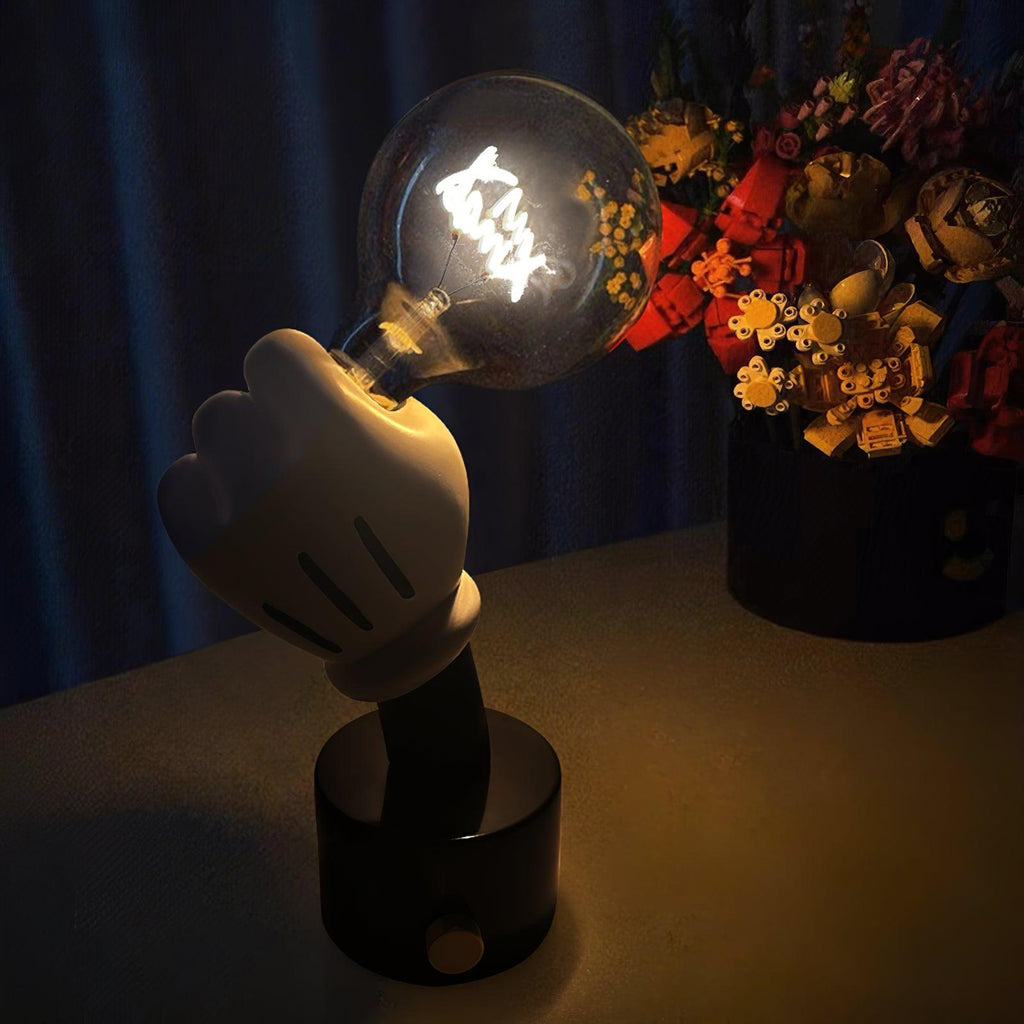 Clérachic novelty table lamp glowing against a dark blue background, its white glove hand raised beside blurred silk flowers.