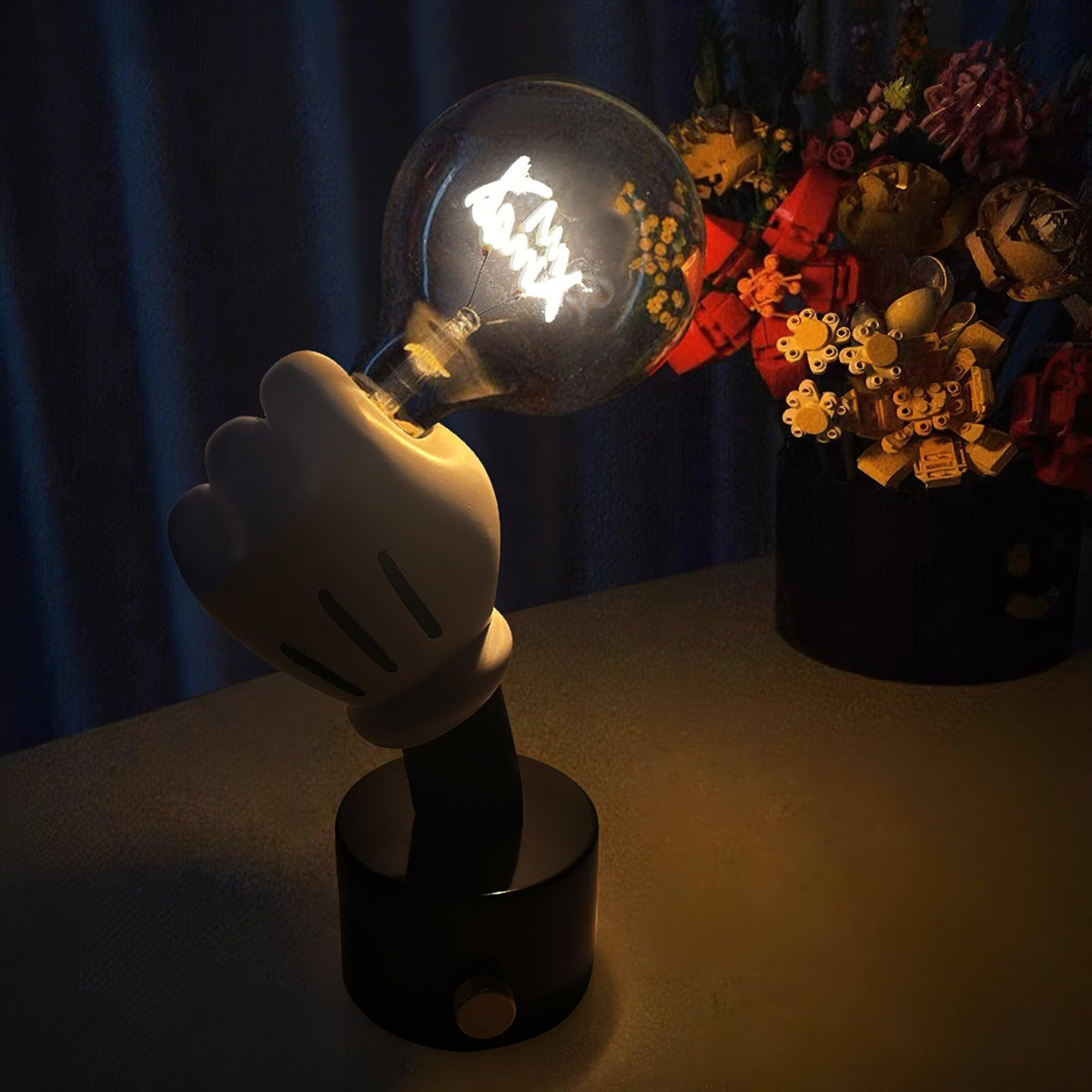 Clérachic novelty table lamp glowing against a dark blue background, its white glove hand raised beside blurred silk flowers.