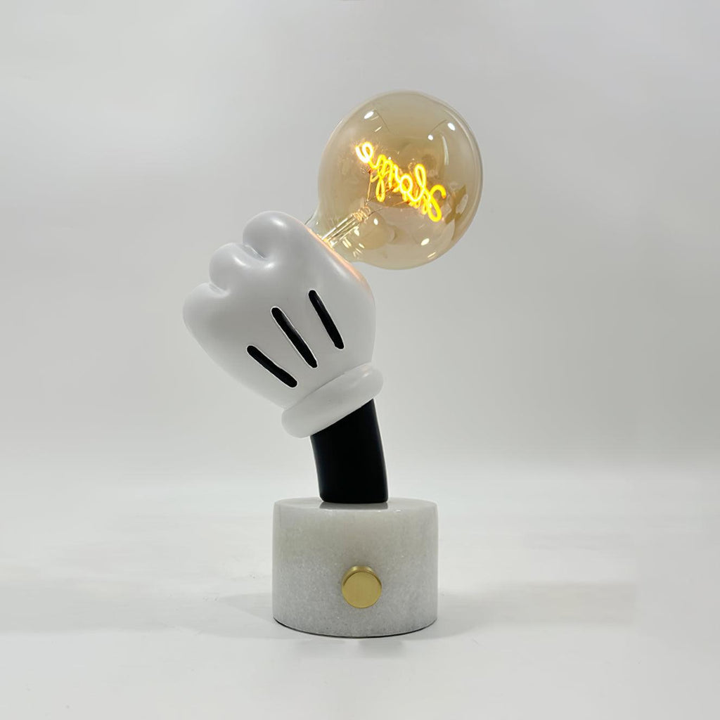A cognac-tinted bulb glows softly atop this Clérachic novelty table lamp, set on white marble against a plain grey background.