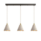 Three tall scalloped cone microcement pendants hung in a row from a dark linear ceiling canopy on braided cords