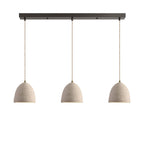 Three small bell dome microcement pendants hung in a row from a dark linear ceiling canopy on braided cords