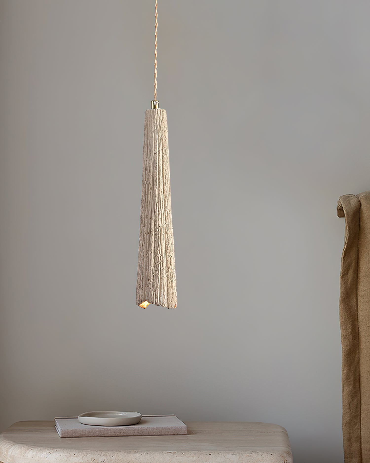 Cement pendant light glowing warm above a counter