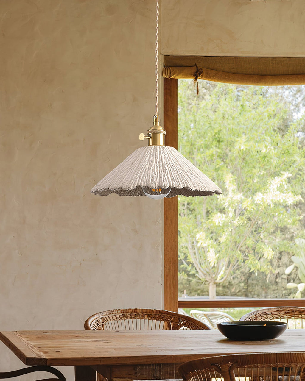 Raw cement pendant light suspended from a braided cord