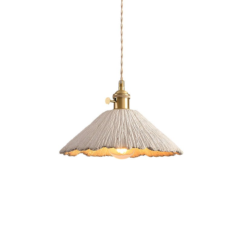 Cement pendant light glowing warmly from a braided cord