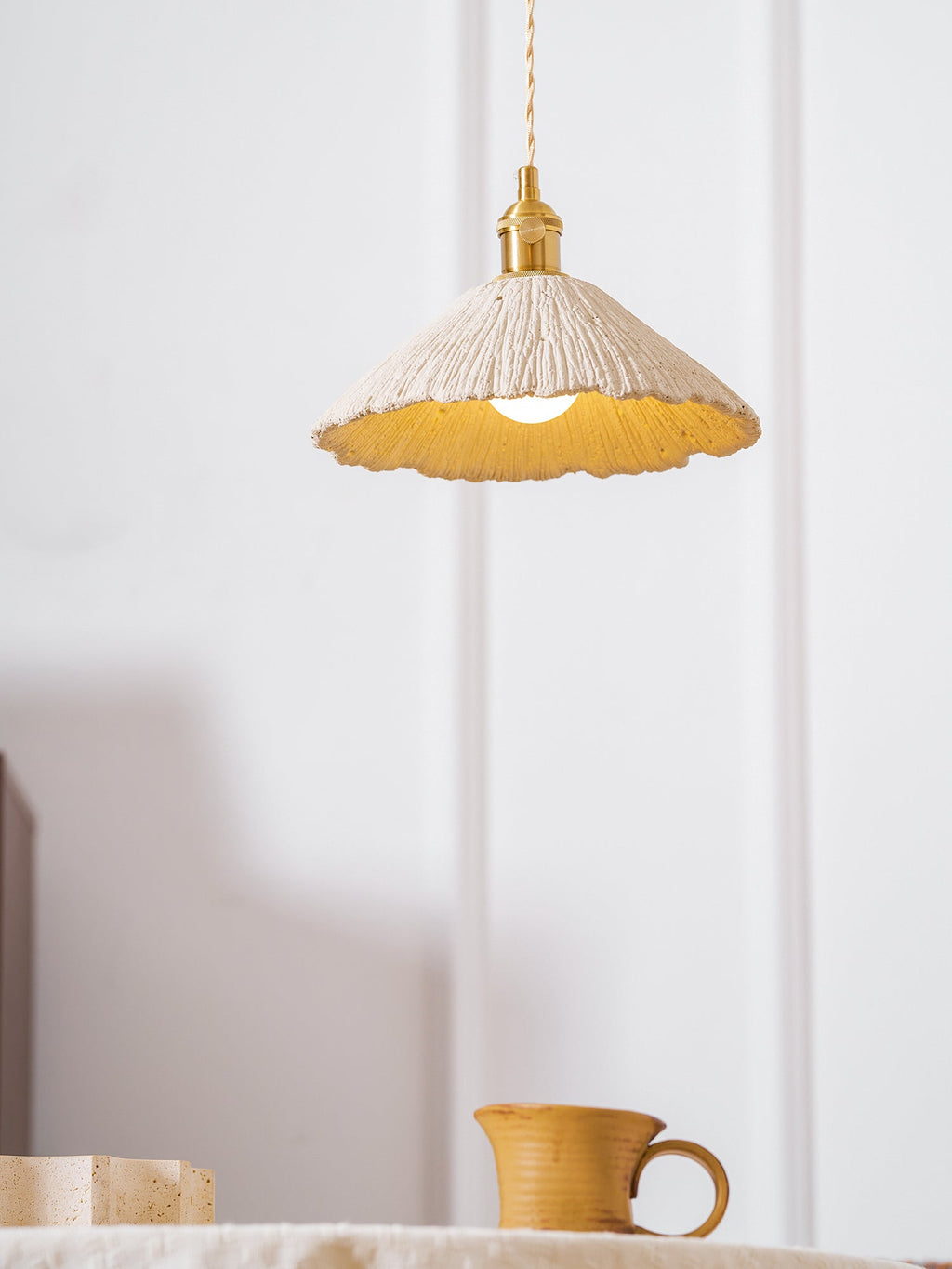 Wide disc cement pendant light suspended from a cord