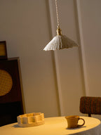 Flat disc microcement pendant light glowing in a room