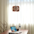 The cube pendant lit above a desk against a sheer curtain, laptop and candle holder below.