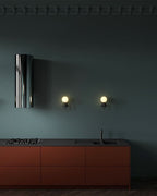 In a wider view of the kitchen, two black Clérachic wall lights glow beside a chrome extractor hood above rust-coloured cabinets.