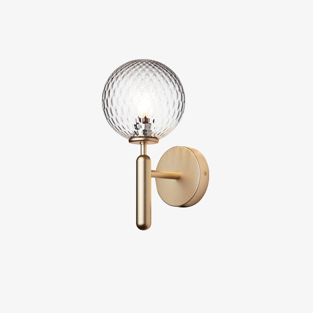 A small view of this brass Clérachic wall light shows its lit dimpled clear glass globe against a plain white background.