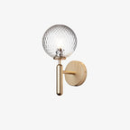 A small view of this brass Clérachic wall light shows its lit dimpled clear glass globe against a plain white background.
