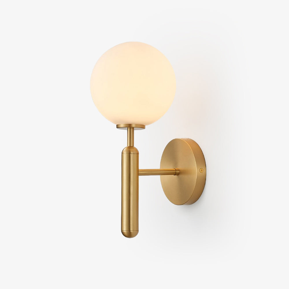 This brass Clérachic wall light stands unlit against a plain light grey background, its white glass globe clearly shown.