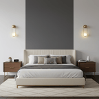 A pair of brass Clérachic wall lights flanks an upholstered bed against a charcoal accent wall.
