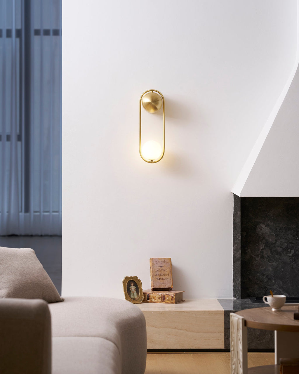 In a living-room corner with a cream sofa and a coffee-table vignette, this brass Clérachic wall light sits on a plain wall unlit.