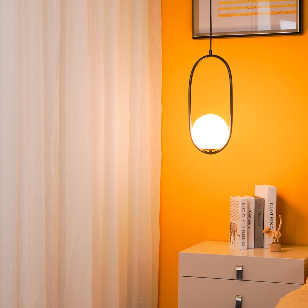 Elongated capsule glass pendant light shown lit warmly