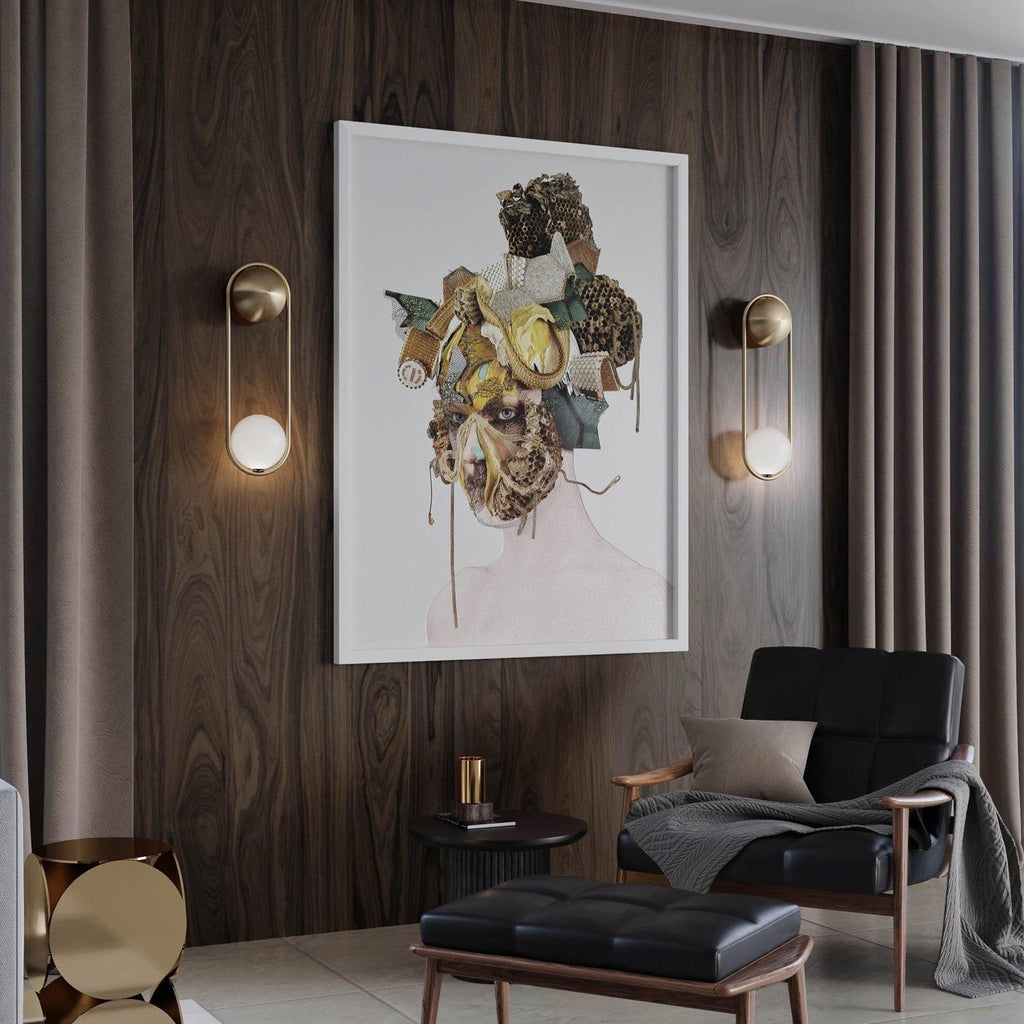 Two brass Clérachic wall lights flank a framed abstract portrait on a wood-panelled wall above a black armchair.