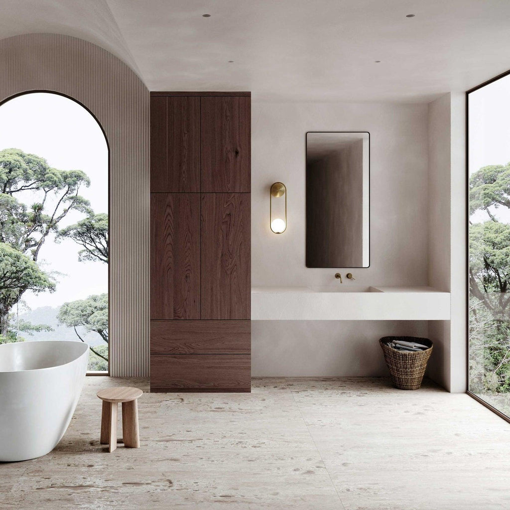 In a spa-style bathroom with a freestanding tub and arched window, this brass Clérachic wall light glows beside a wood vanity.