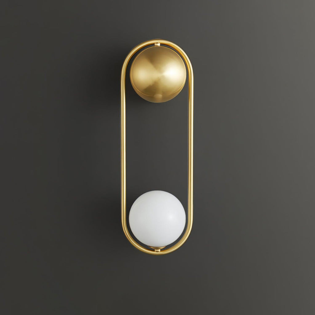 A brass Clérachic wall light on a dark charcoal background, its opal glass globe shown unlit at the base of the oval frame.