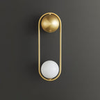 A brass Clérachic wall light on a dark charcoal background, its opal glass globe shown unlit at the base of the oval frame.