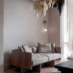 Seen across a living room with a sheer curtain and a hanging dried-flower display, this black-finish Clérachic wall light sits on a plain wall.