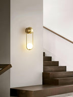 Closer view of the same staircase, this brass Clérachic wall light glows warm beside the wooden steps.