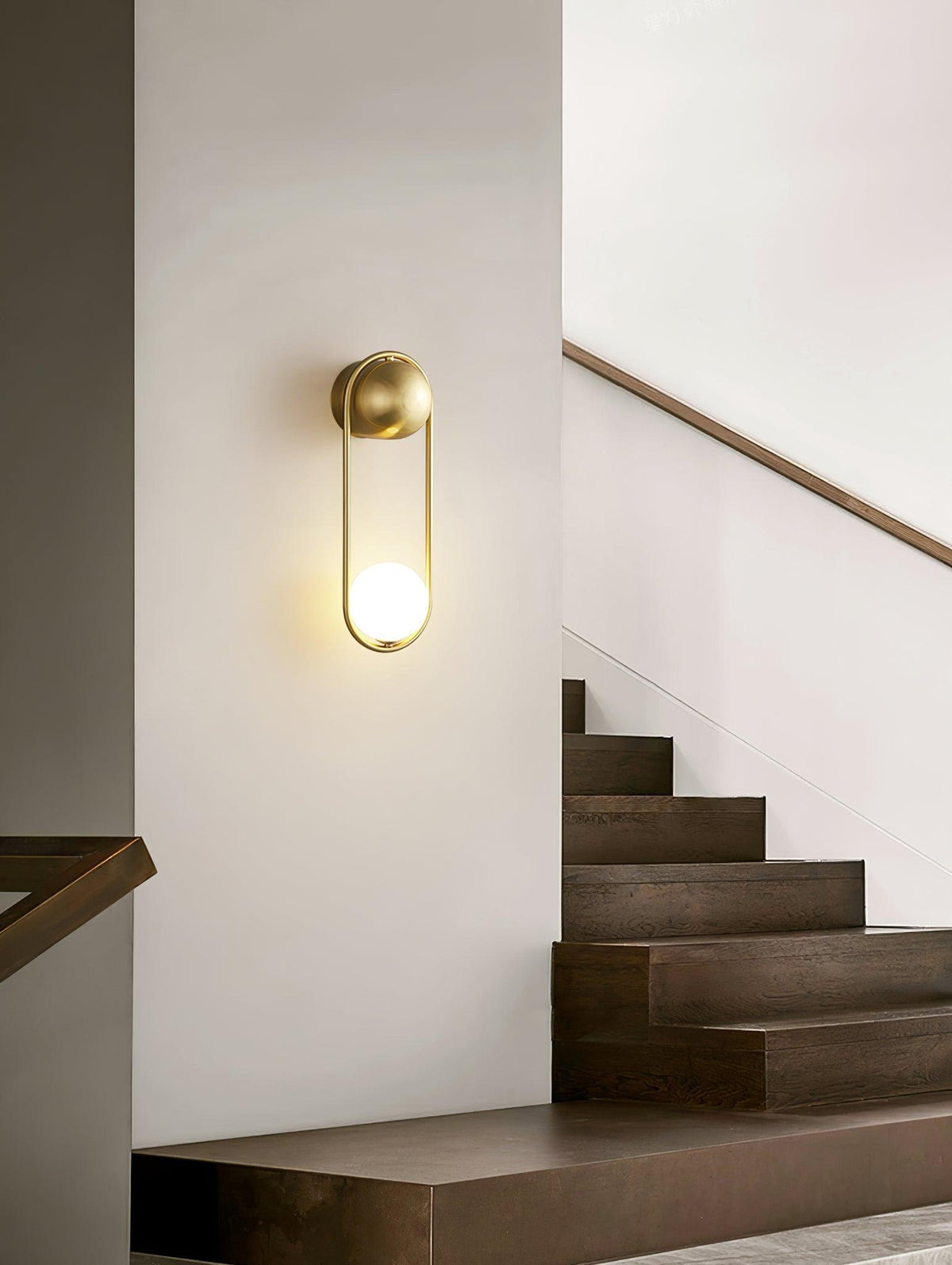 Closer view of the same staircase, this brass Clérachic wall light glows warm beside the wooden steps.