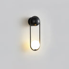 A black-finish Clérachic wall light on a plain grey background, its opal glass globe glowing at the base.