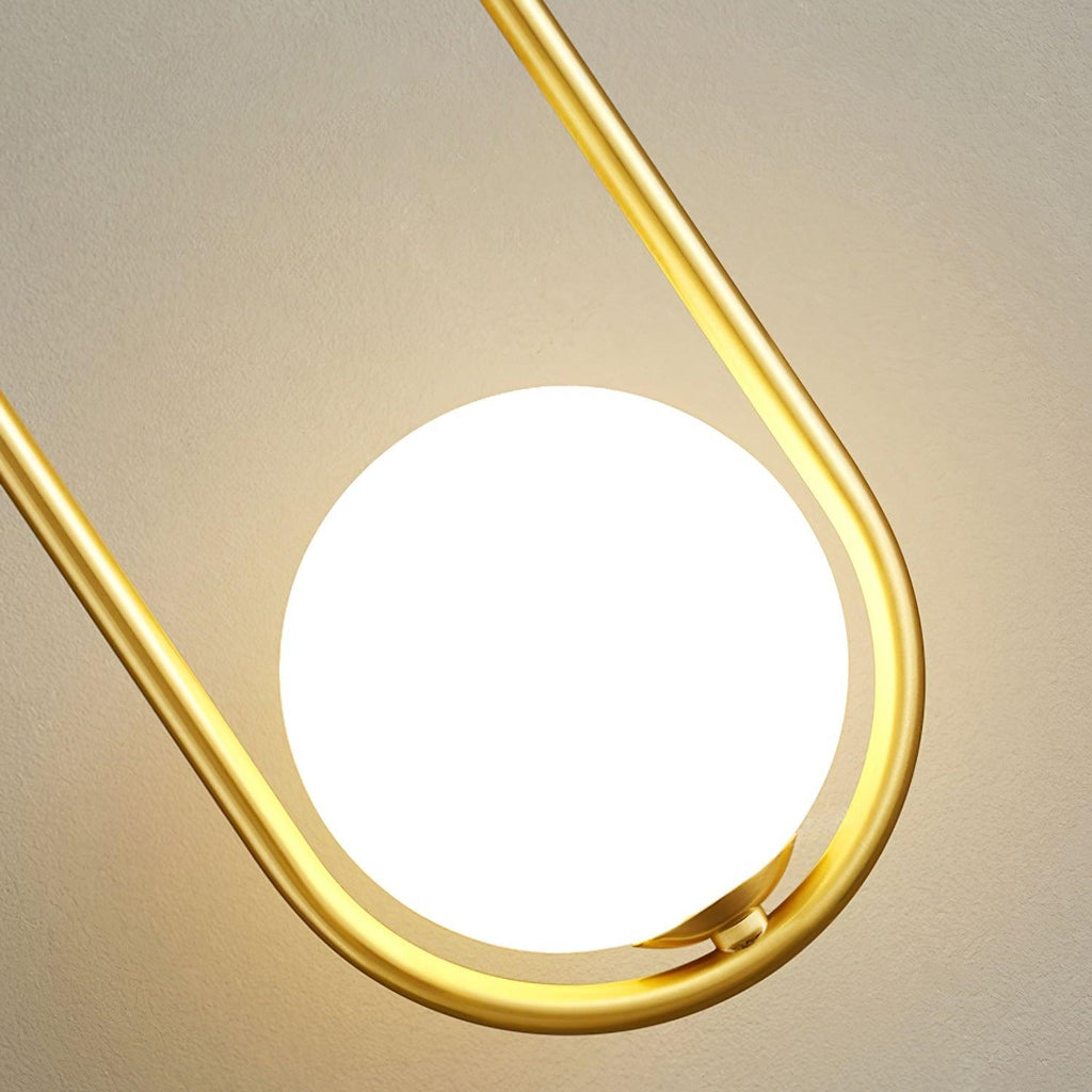 Dramatic close-up from below of this Clérachic wall light, its opal glass globe glowing warm inside the brass loop.