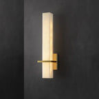 Alabaster wall light lit against a dark charcoal wall, brass arm extending to the left