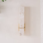 Straight-on view of the unlit wall light, brass crossbar crossing the alabaster face
