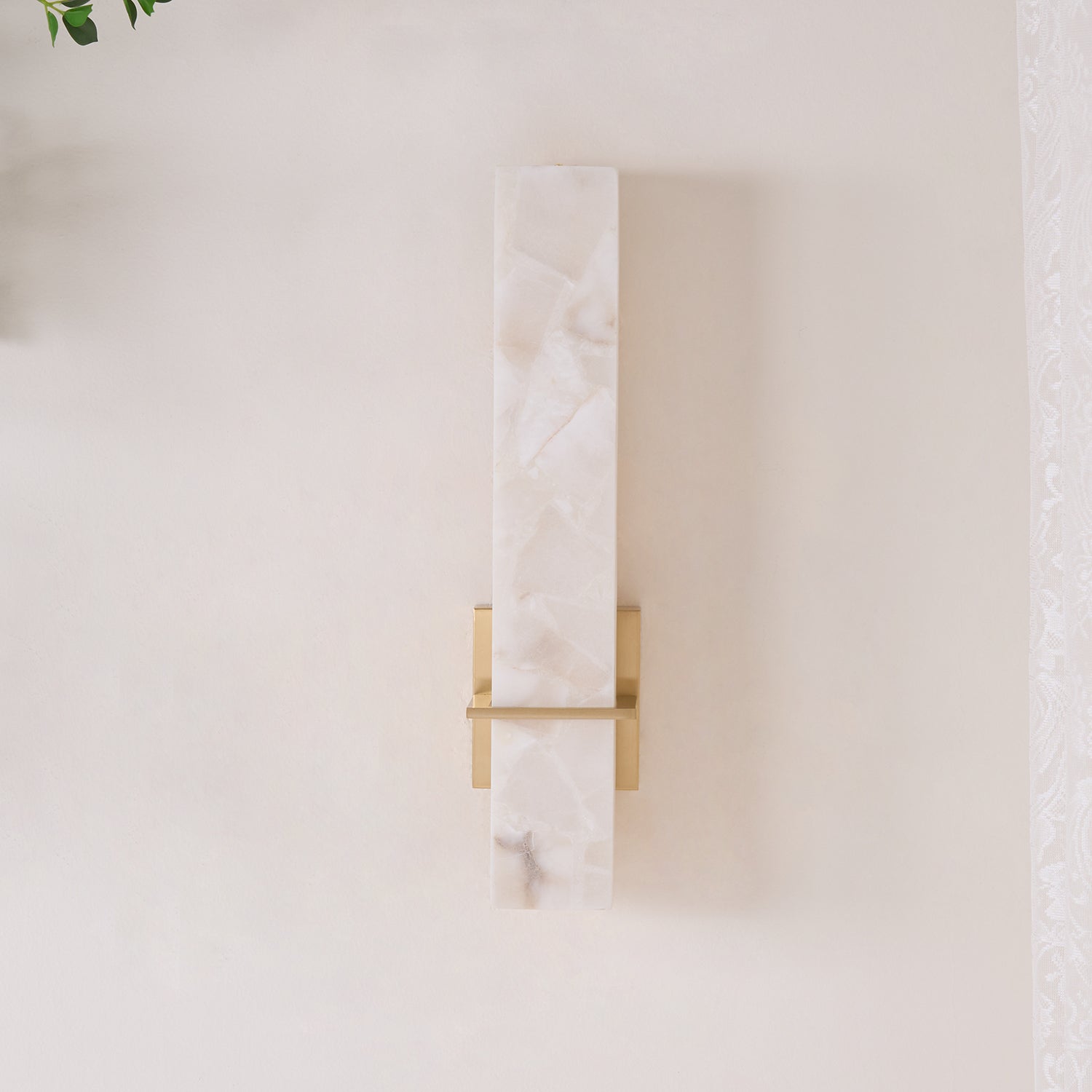 Straight-on view of the unlit wall light, brass crossbar crossing the alabaster face
