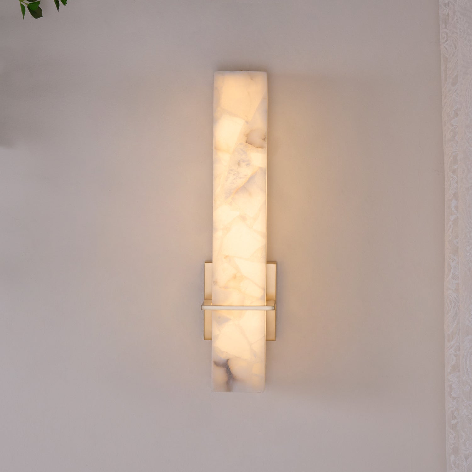 Straight-on view of the wall light switched on, warm glow through the mosaic alabaster face