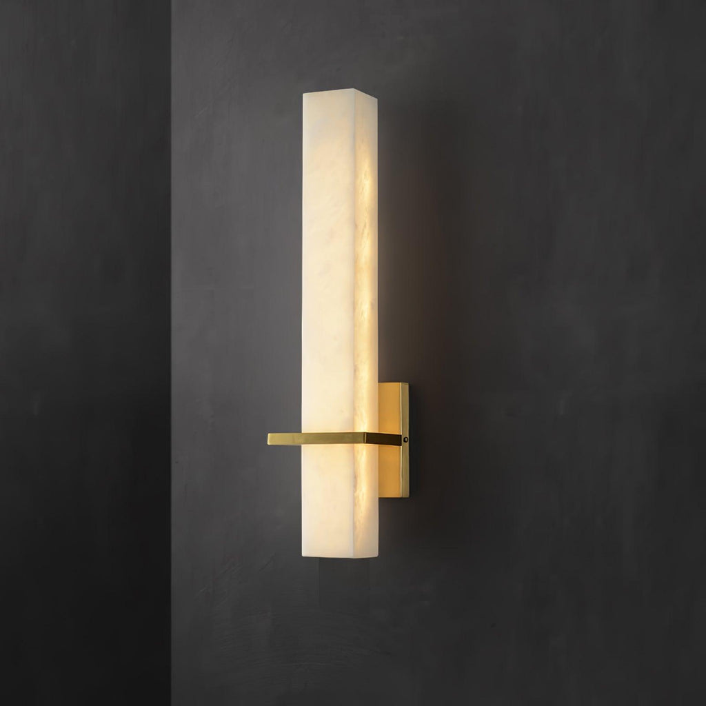 The lit alabaster block against dark plaster, polished brass bar crossing at its lower third