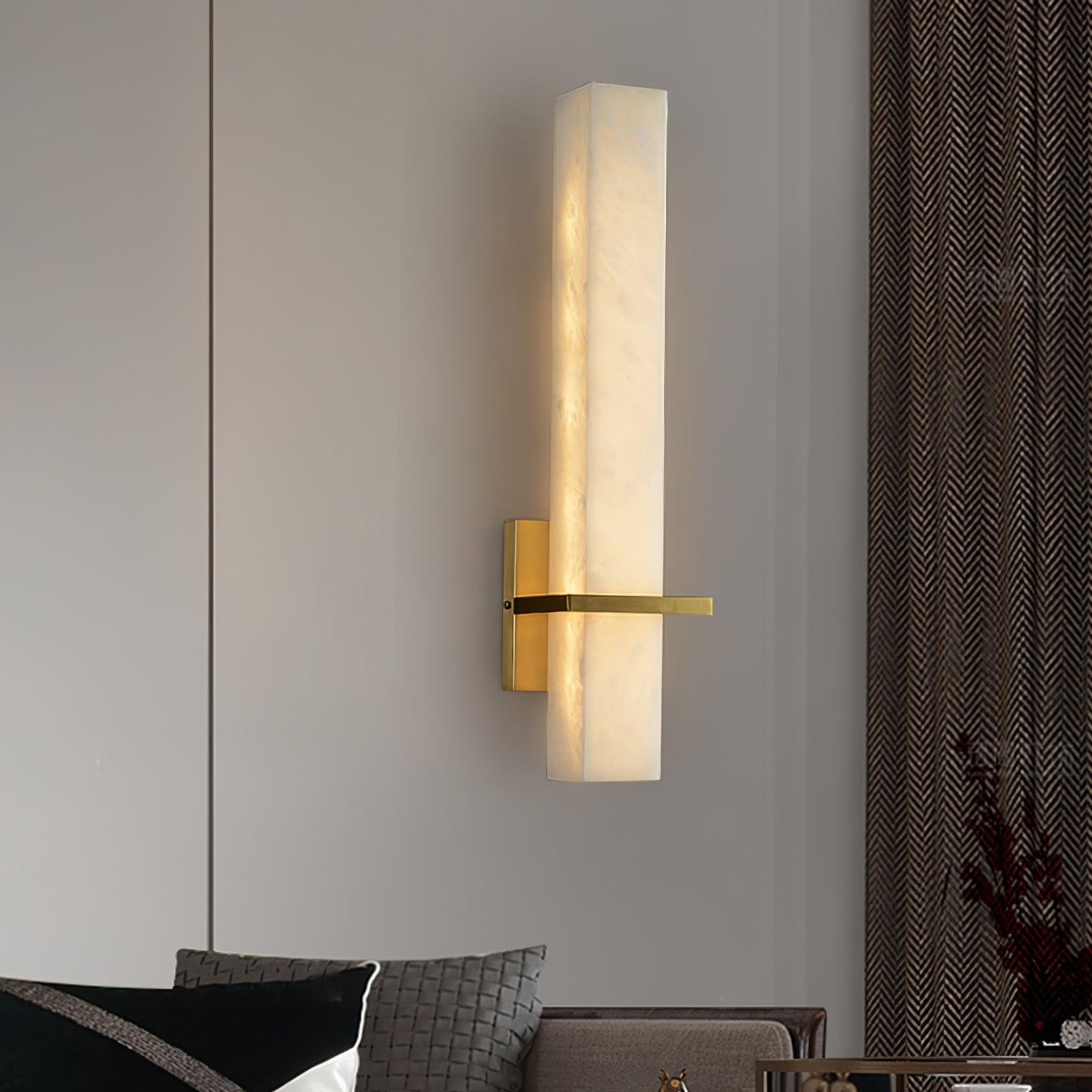 Alabaster wall light lit in a living room beside wardrobe doors, above a sofa with patterned cushions
